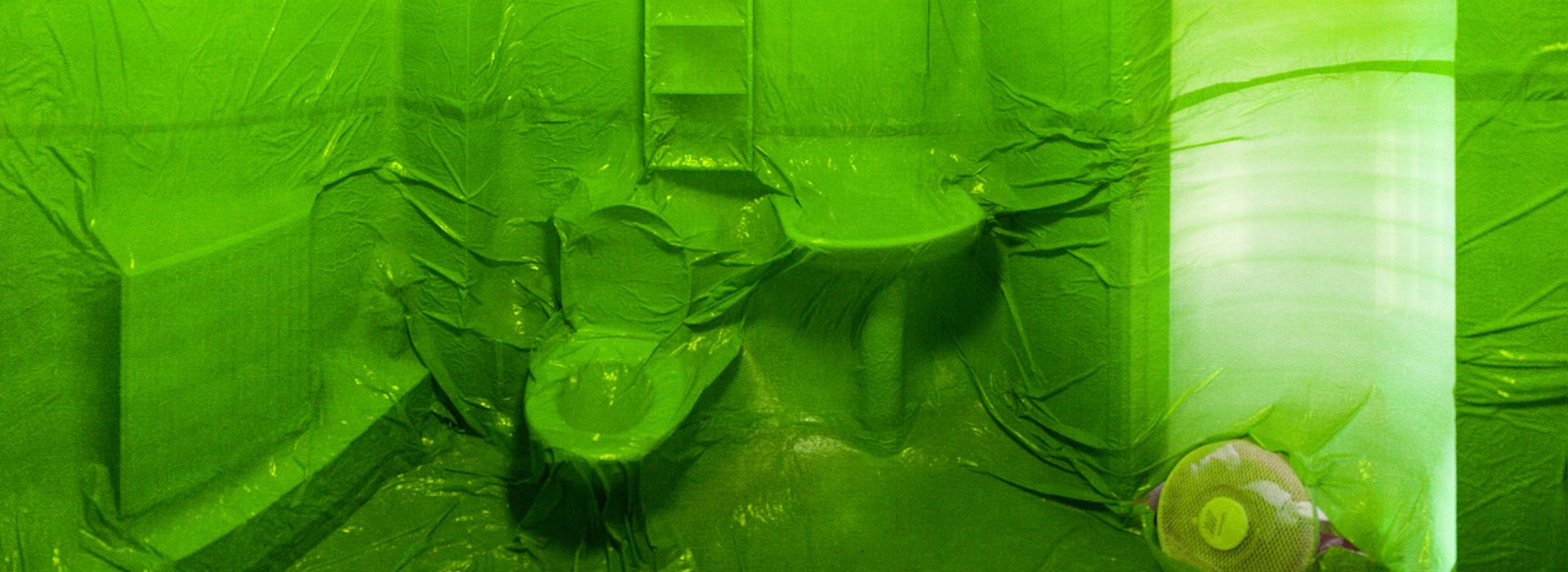 This is a promotional image for After The End, displaying a plastic-wrapped bathroom with green lighting.