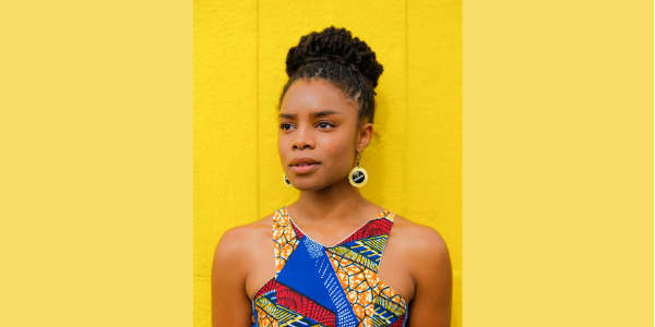 Photo of Justina Kehinde. Justina is looking into the distance, wearing a colourful top.