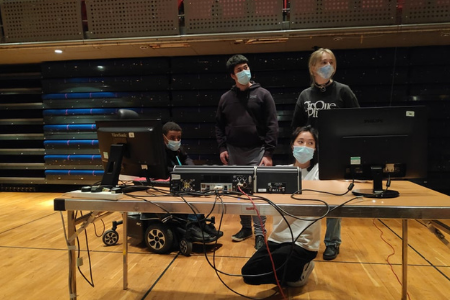 Course participants around a table looking at a lighting desk.