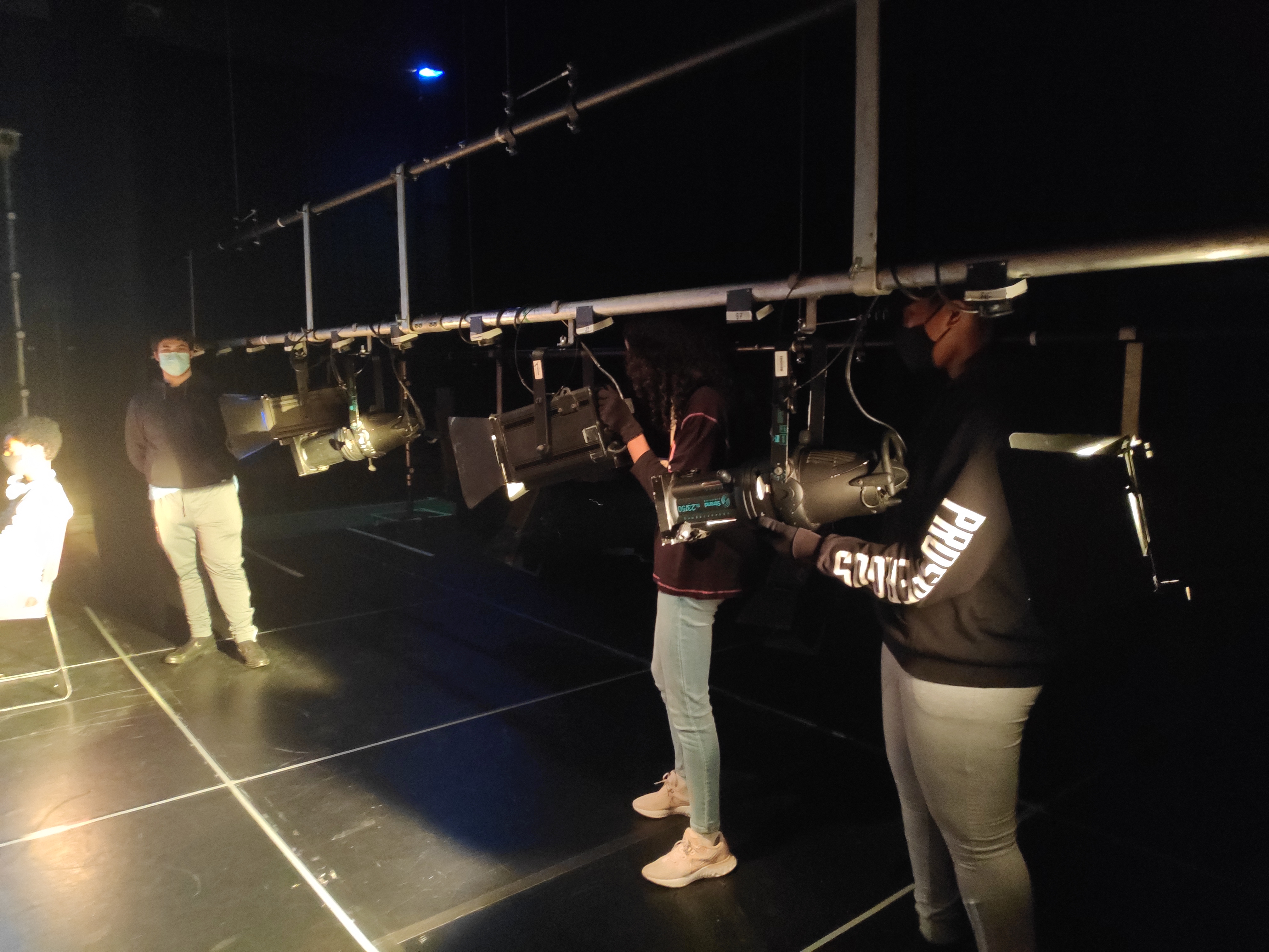 Photo of young technicians holding lights in the lighting rig